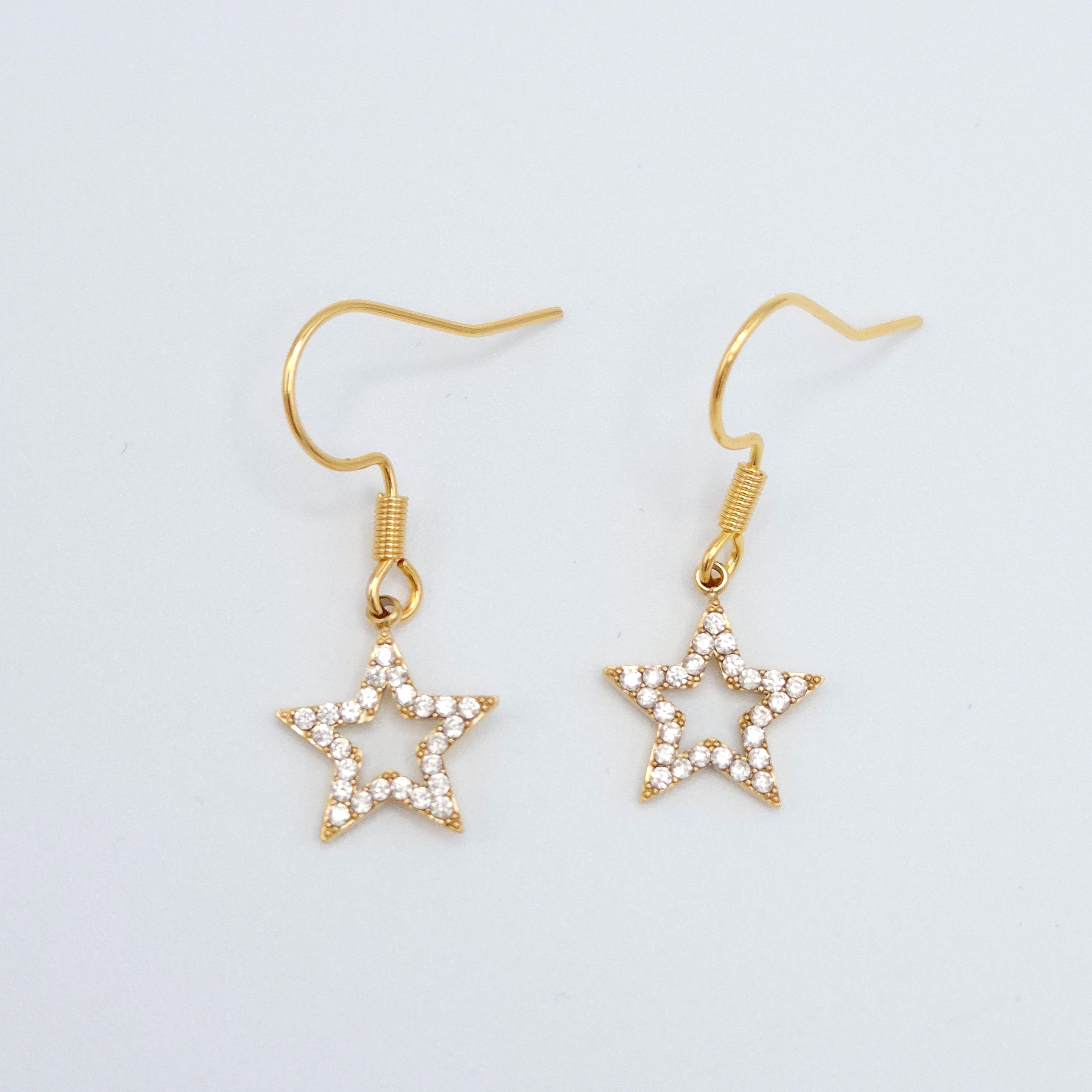 Detalle pendientes estrella dorados acabado brillante